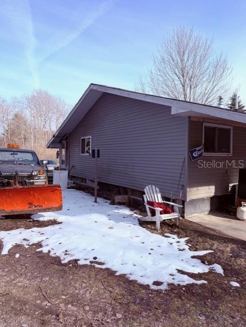 A side view of a house with gray siding, a snow-covered yard, and a parked truck — 5297 N HUGHES AVENUE, FOUNTAIN, MI