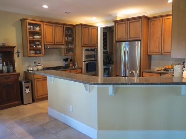 A kitchen features wood cabinets, a granite-topped breakfast bar, and stainless steel appliances — 3103 W WAVERLY AVENUE, TAMPA, FL