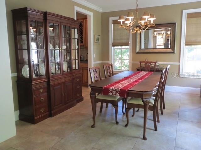 A dining room features a large wooden china cabinet, a table with a red runner, and chandelier — 3103 W WAVERLY AVENUE, TAMPA, FL