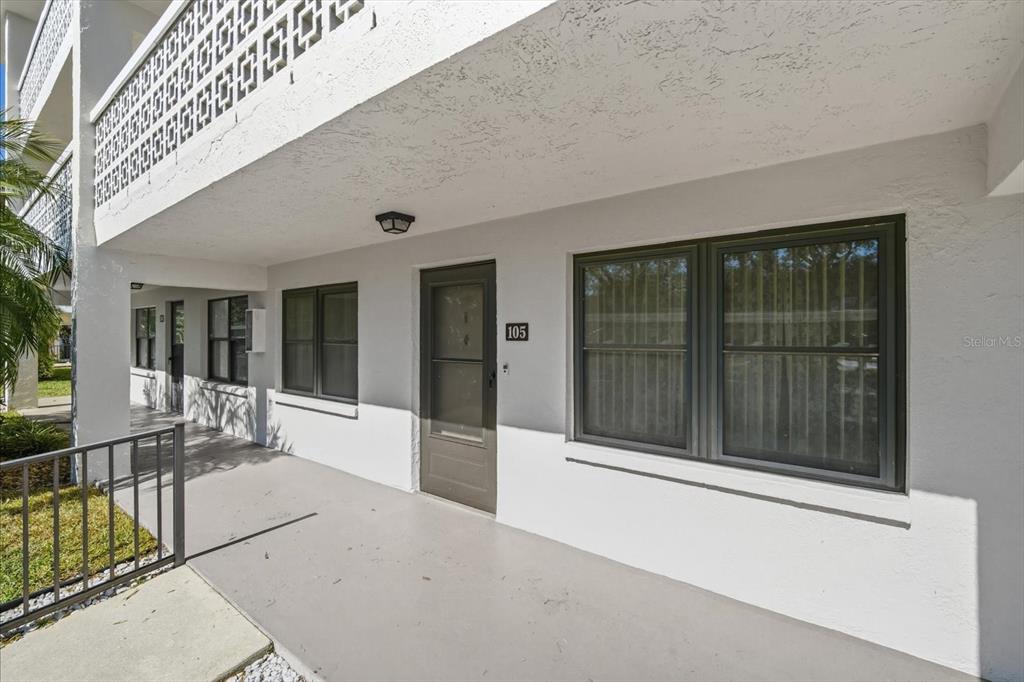 The exterior view shows the entrance to a ground-floor apartment unit with a covered walkway — 4910 BAY STREET NE UNIT 105, ST PETERSBURG, FL