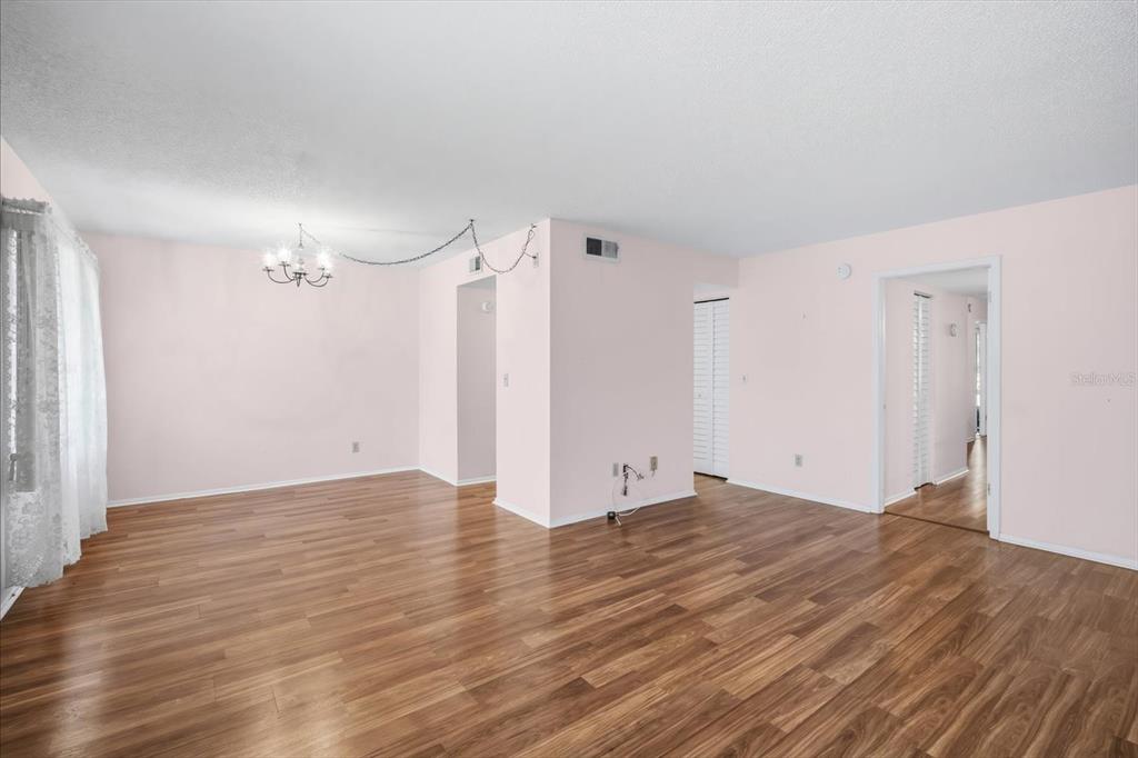An empty room with light pink walls, wood-look flooring, and a hanging light fixture — 4910 BAY STREET NE UNIT 105, ST PETERSBURG, FL