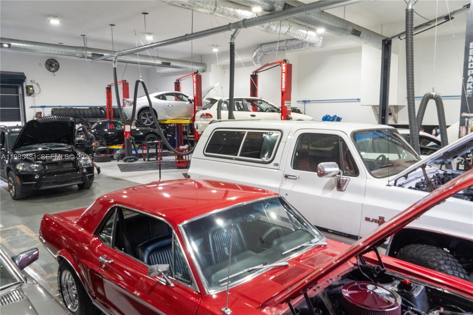 A spacious automotive repair shop features multiple vehicle lifts and several cars under maintenance — 5836 Rodman St, Hollywood FL 33023, HOLLYWOOD, FL