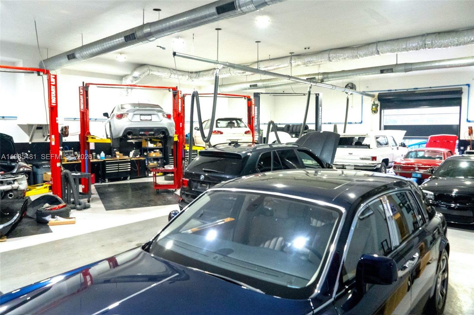A spacious automotive repair shop features multiple vehicle lifts and several cars parked inside — 5836 Rodman St, Hollywood FL 33023, HOLLYWOOD, FL