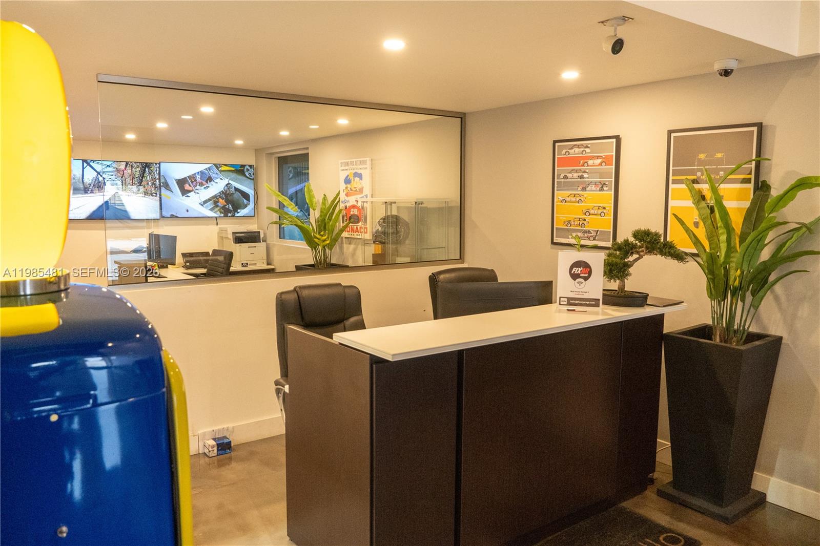 A reception area features a dark desk, two chairs, wall art, and a glass partition — 5836 Rodman St, Hollywood FL 33023, HOLLYWOOD, FL