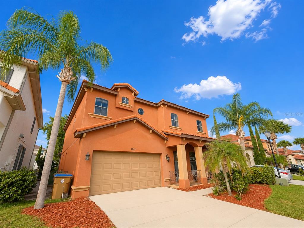 A two-story orange stucco house with a two-car garage and palm trees in the yard — 2807 VIA LARGO COURT, KISSIMMEE, FL