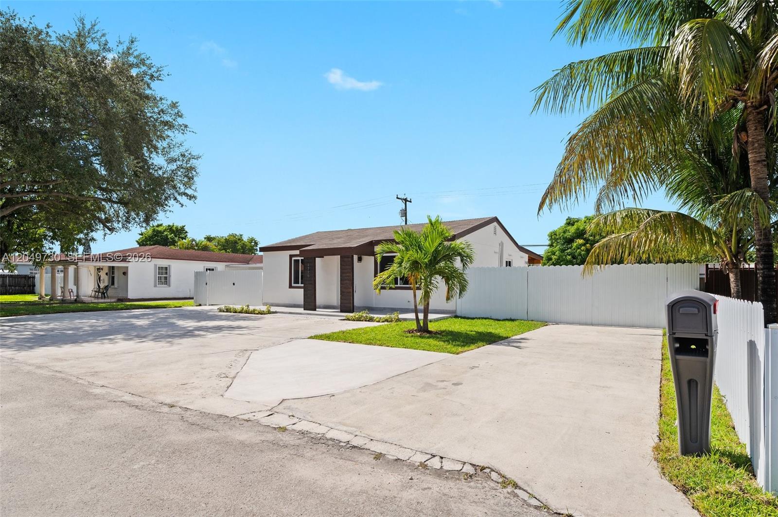 A single-story house with a white fence and a large concrete driveway — 1720 NW 67th St, Miami FL 33147, MIAMI, FL