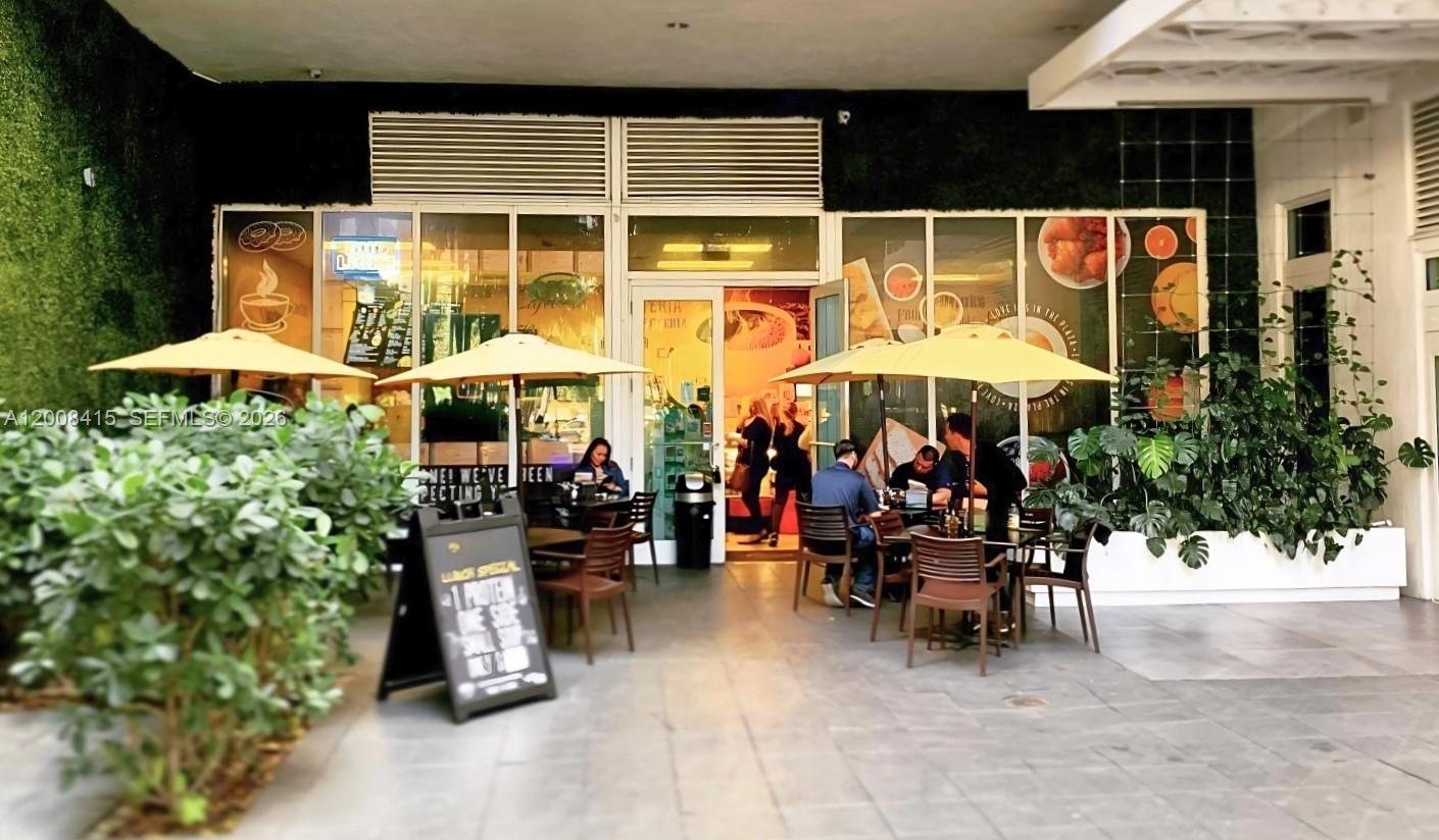 An outdoor patio area with tables, umbrellas, and chairs in front of a restaurant entrance — XXXX BRICKELL AVE, Miami FL 33131, MIAMI, FL