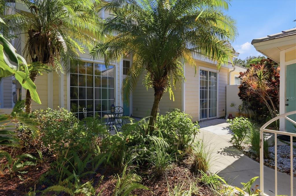 A yellow house exterior features a patio, palm trees, and sliding glass doors — 7630 WHITEBRIDGE GLEN, UNIVERSITY PARK, FL
