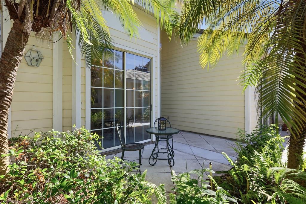 A small patio with a bistro table and chair sits outside a sliding glass door — 7630 WHITEBRIDGE GLEN, UNIVERSITY PARK, FL