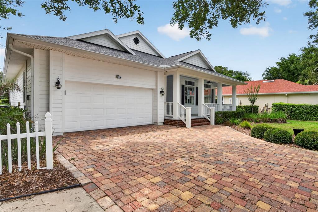 A single-story house with a white exterior, a brick paver driveway, and a front porch — 4 CHINIER STREET, PALM COAST, FL