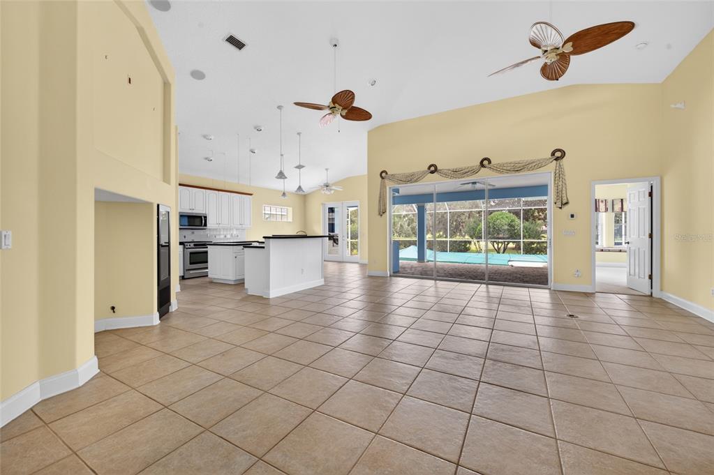 A large, open-concept living area with tile flooring, vaulted ceilings, and a kitchen with island — 4 CHINIER STREET, PALM COAST, FL
