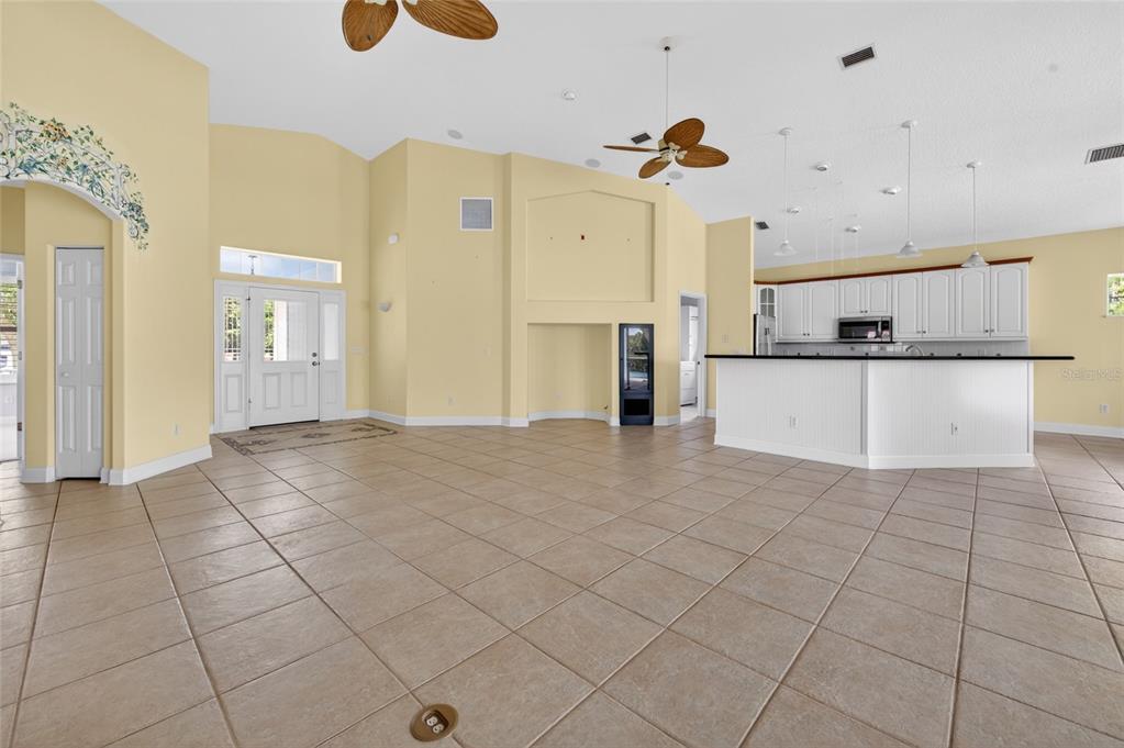 A spacious, open-concept living area with tile flooring, yellow walls, and an attached kitchen — 4 CHINIER STREET, PALM COAST, FL