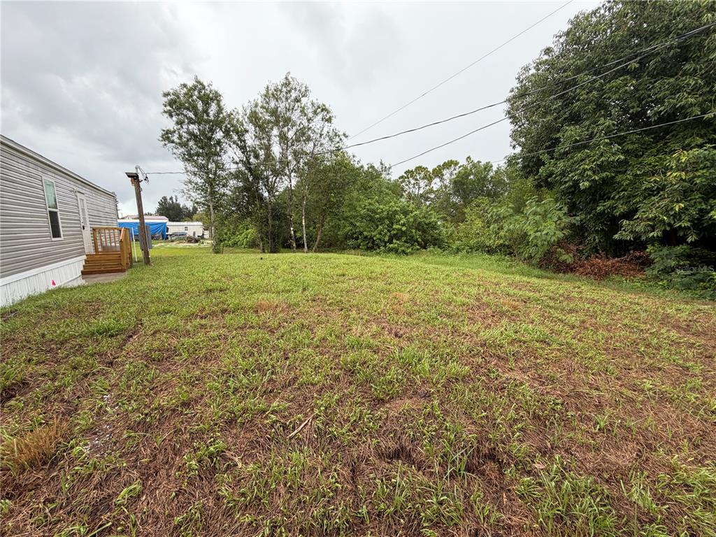 A grassy, undeveloped lot sits adjacent to the side of a mobile home — 15492 MANGO DRIVE, PUNTA GORDA, FL