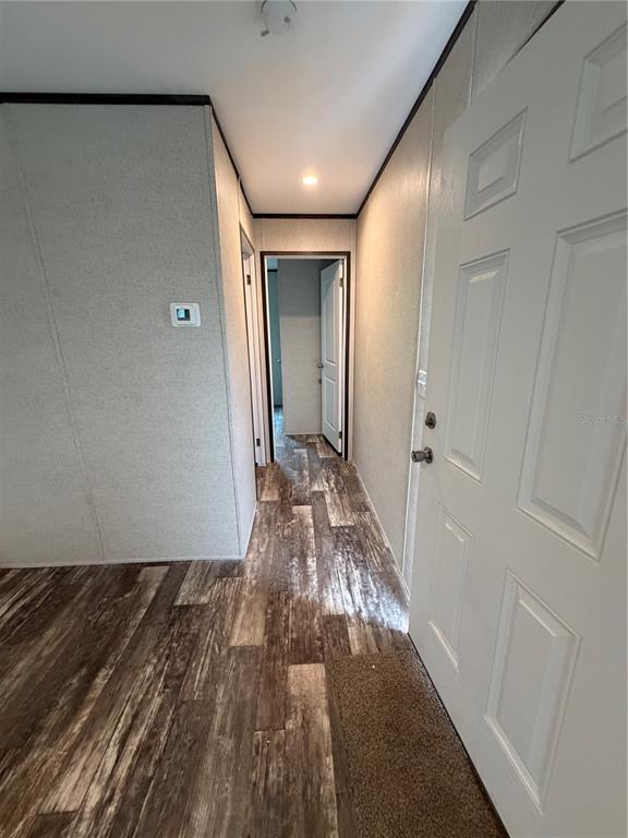 A hallway with wood-look flooring leads to a doorway in a home with paneled walls — 15492 MANGO DRIVE, PUNTA GORDA, FL