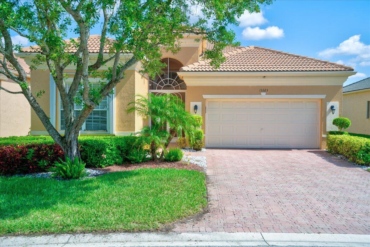 A single-story house with a tan stucco exterior, a tiled roof, and a paved driveway — 15323 Fiorenza Circle, Delray Beach FL 33446, DELRAY BEACH, FL