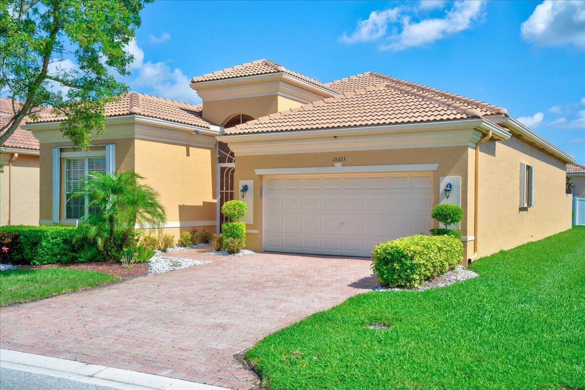A single-story house with a beige stucco exterior, a tiled roof, and a paved driveway — 15323 Fiorenza Circle, Delray Beach FL 33446, DELRAY BEACH, FL