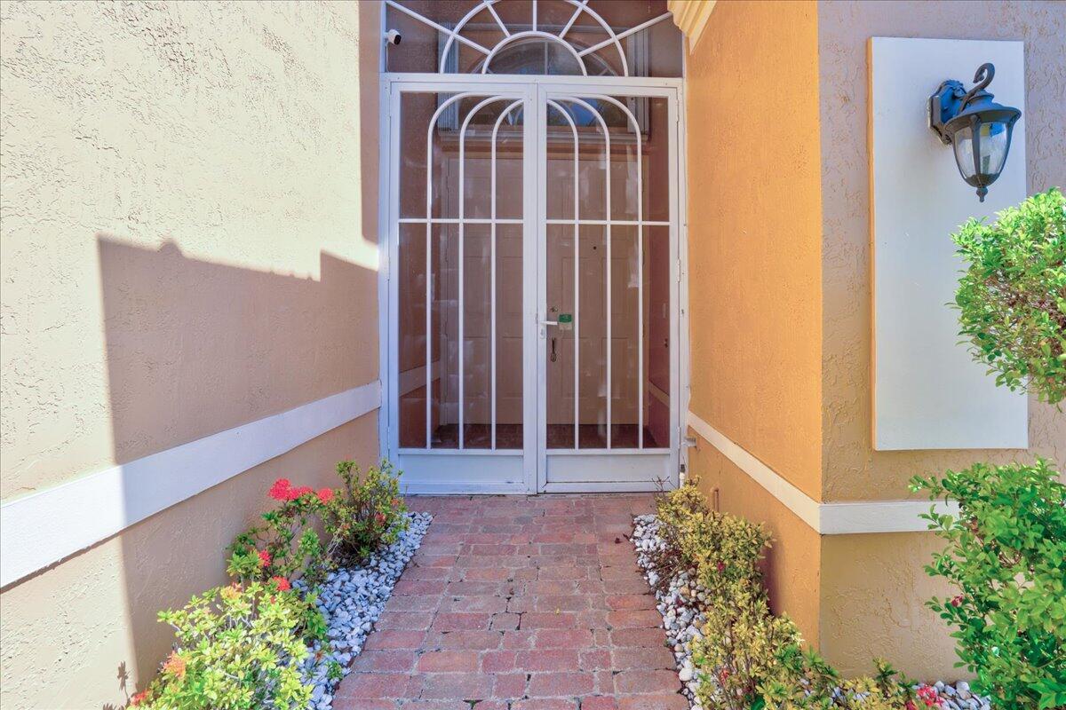 A brick walkway leads to a white double storm door at the entrance of a house — 15323 Fiorenza Circle, Delray Beach FL 33446, DELRAY BEACH, FL