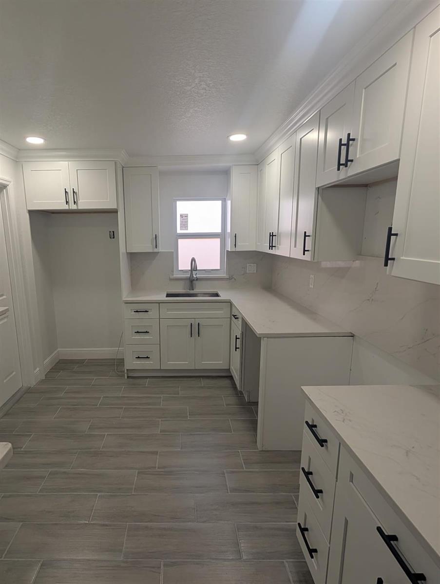 A kitchen features white shaker cabinets, quartz countertops, and gray wood-look tile flooring — 7713 Kimberly Boulevard, North Lauderdale FL 33068, NORTH LAUDERDALE, FL