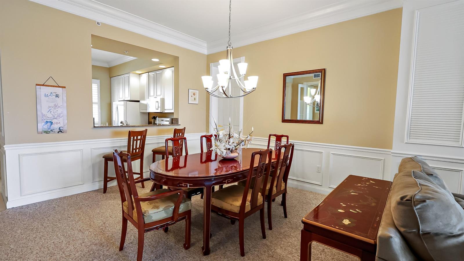 A dining room features a wooden table, chairs, a chandelier, and a kitchen pass-through window — 4 E Harbour Isle Drive E, Fort Pierce FL 34949, FORT PIERCE, FL