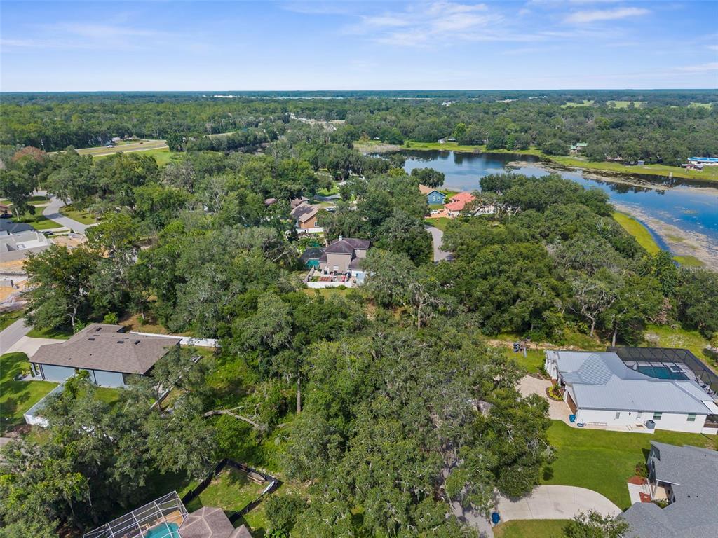 An aerial view shows several houses nestled among dense trees near a large lake — 0 SHOREWOOD DRIVE, DADE CITY, FL