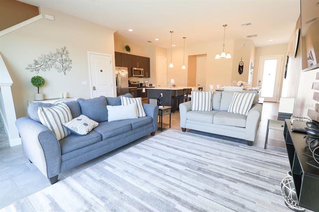 A living room with two sofas, a striped rug, and an open kitchen in the background — 216 VILLA DOMANI CIRCLE, DAVENPORT, FL