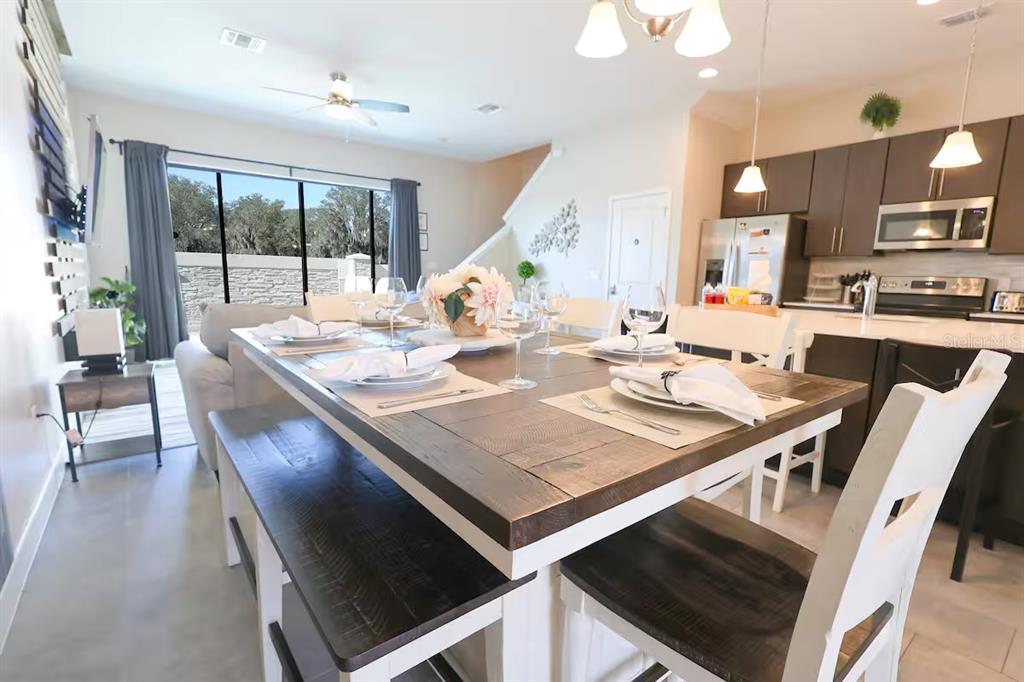 A dining area with a wooden table and benches sits in front of an open kitchen — 216 VILLA DOMANI CIRCLE, DAVENPORT, FL