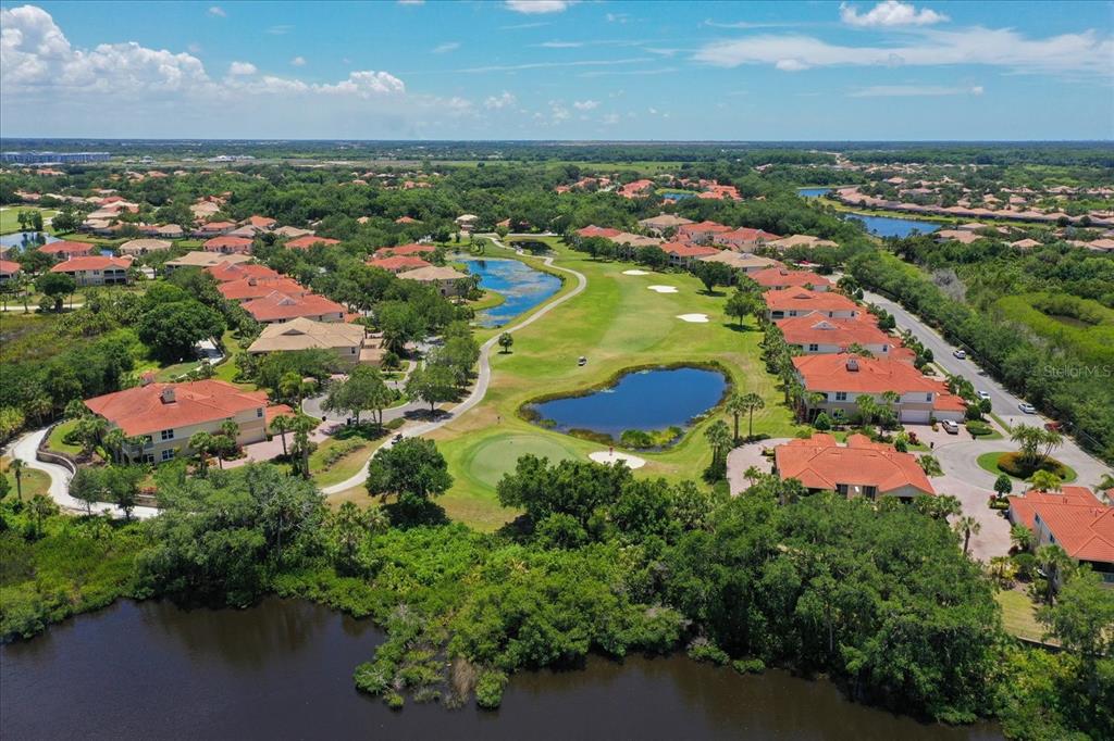 An aerial view of a residential community featuring a golf course, ponds, and tile-roofed homes — 9411 DISCOVERY TERRACE UNIT 102B, BRADENTON, FL