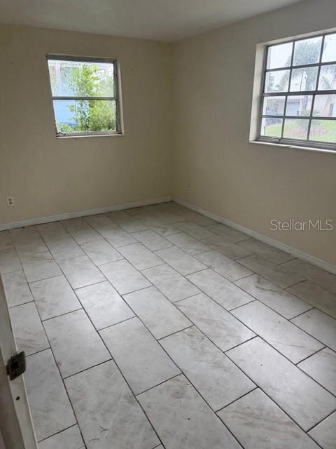 An empty room with light-colored tile flooring and two windows — 3331 CLYDESDALE DRIVE, HOLIDAY, FL