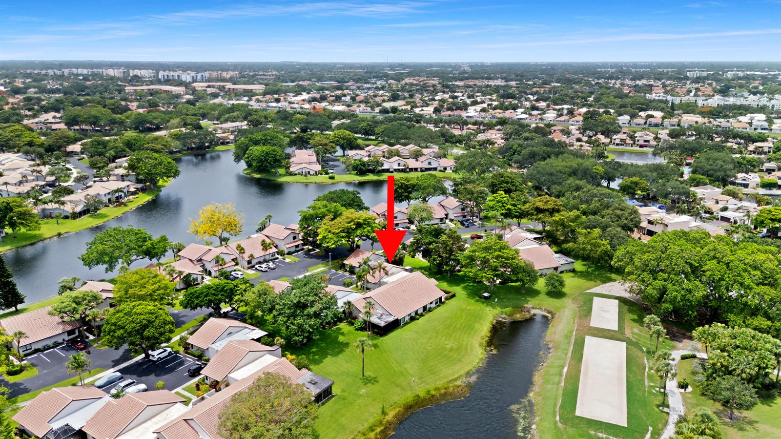 An aerial view shows a residential complex with tile-roofed buildings, a lake, and green lawns — 3018 Lakeshore Drive, Deerfield Beach FL 33442, DEERFIELD BEACH, FL