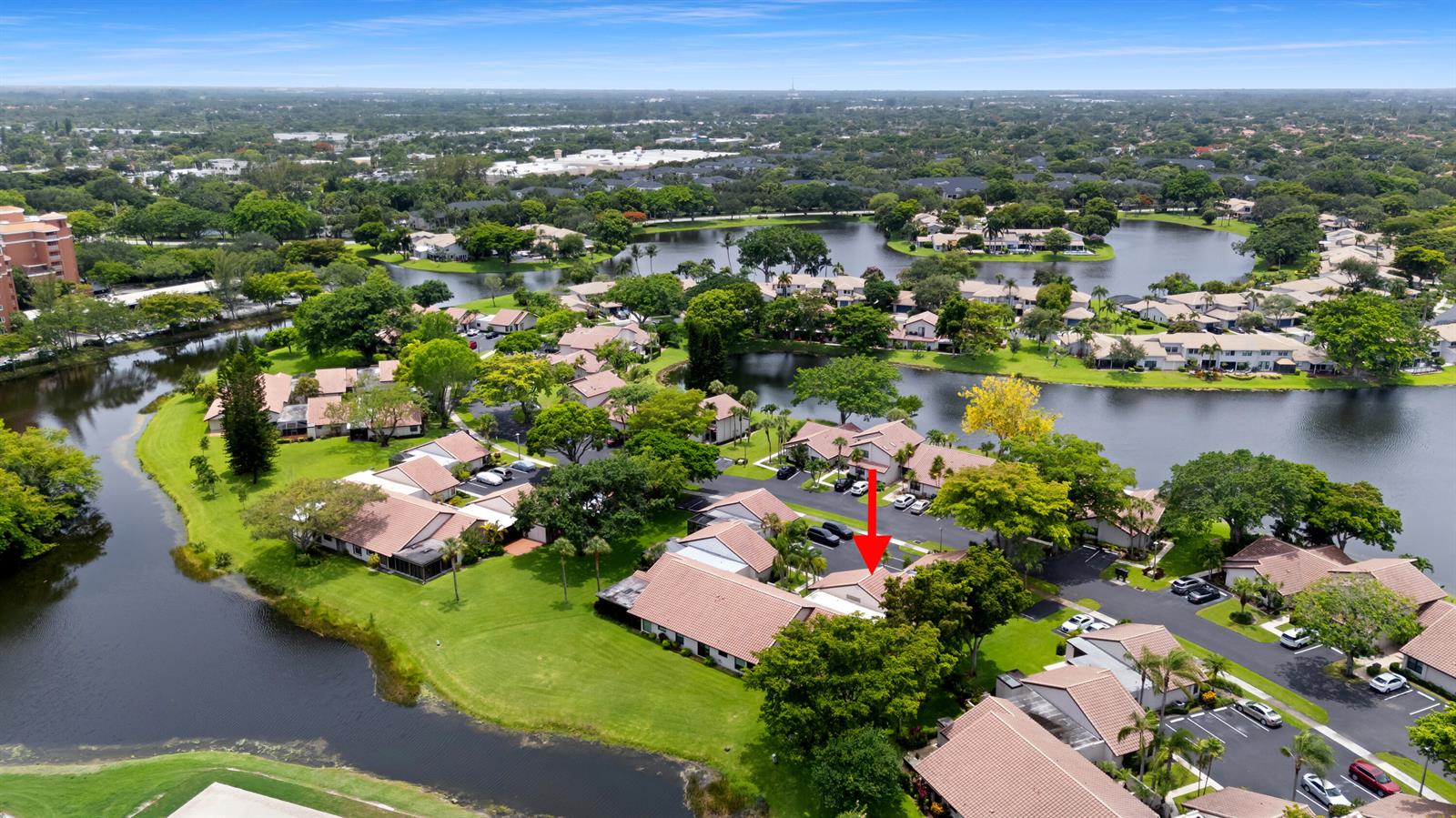 An aerial view shows a residential community with tile-roofed buildings surrounded by lakes and trees — 3018 Lakeshore Drive, Deerfield Beach FL 33442, DEERFIELD BEACH, FL