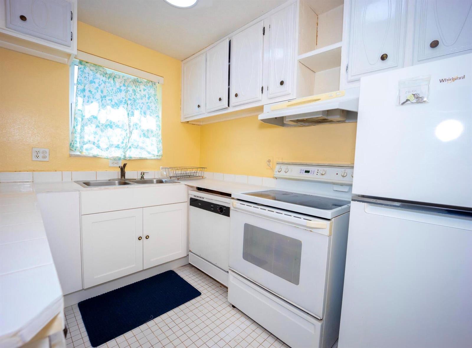 A kitchen features white cabinets, yellow walls, a white stove, and a white refrigerator — 3240 Ridge Hill Road # C, Boynton Beach FL 33435, BOYNTON BEACH, FL