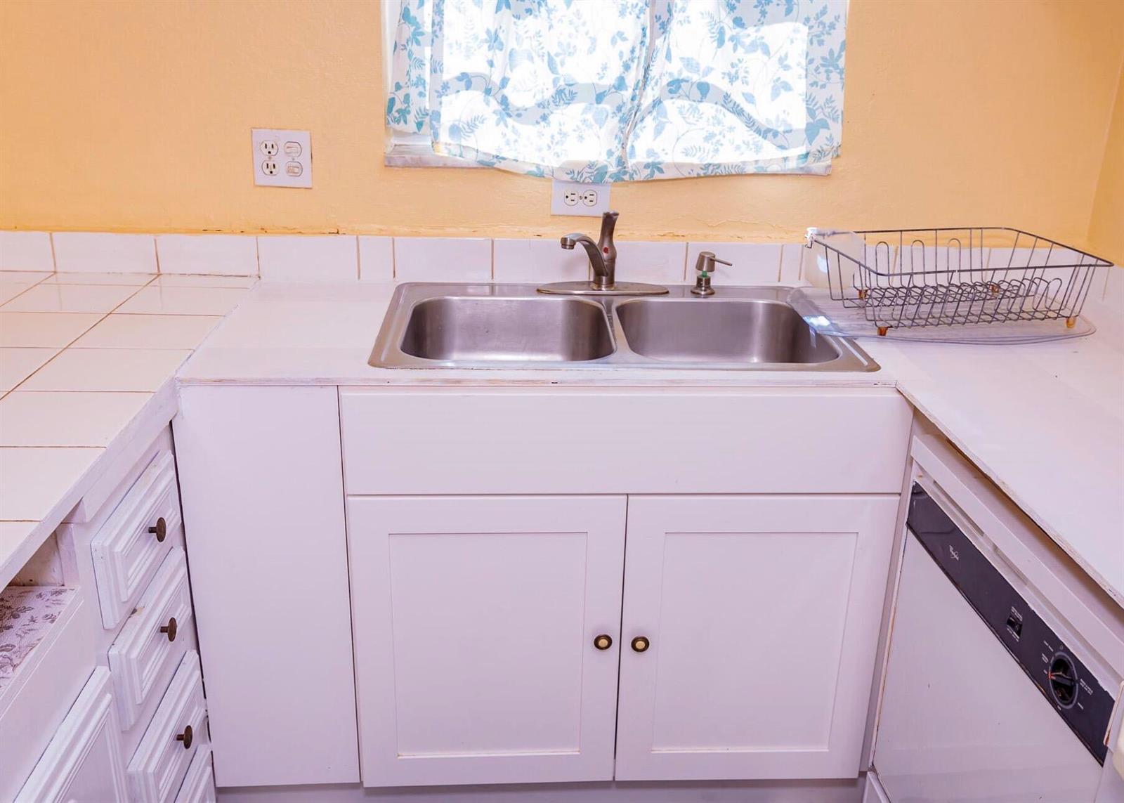 A kitchen features a double-basin stainless steel sink, white cabinets, and a tiled countertop — 3240 Ridge Hill Road # C, Boynton Beach FL 33435, BOYNTON BEACH, FL