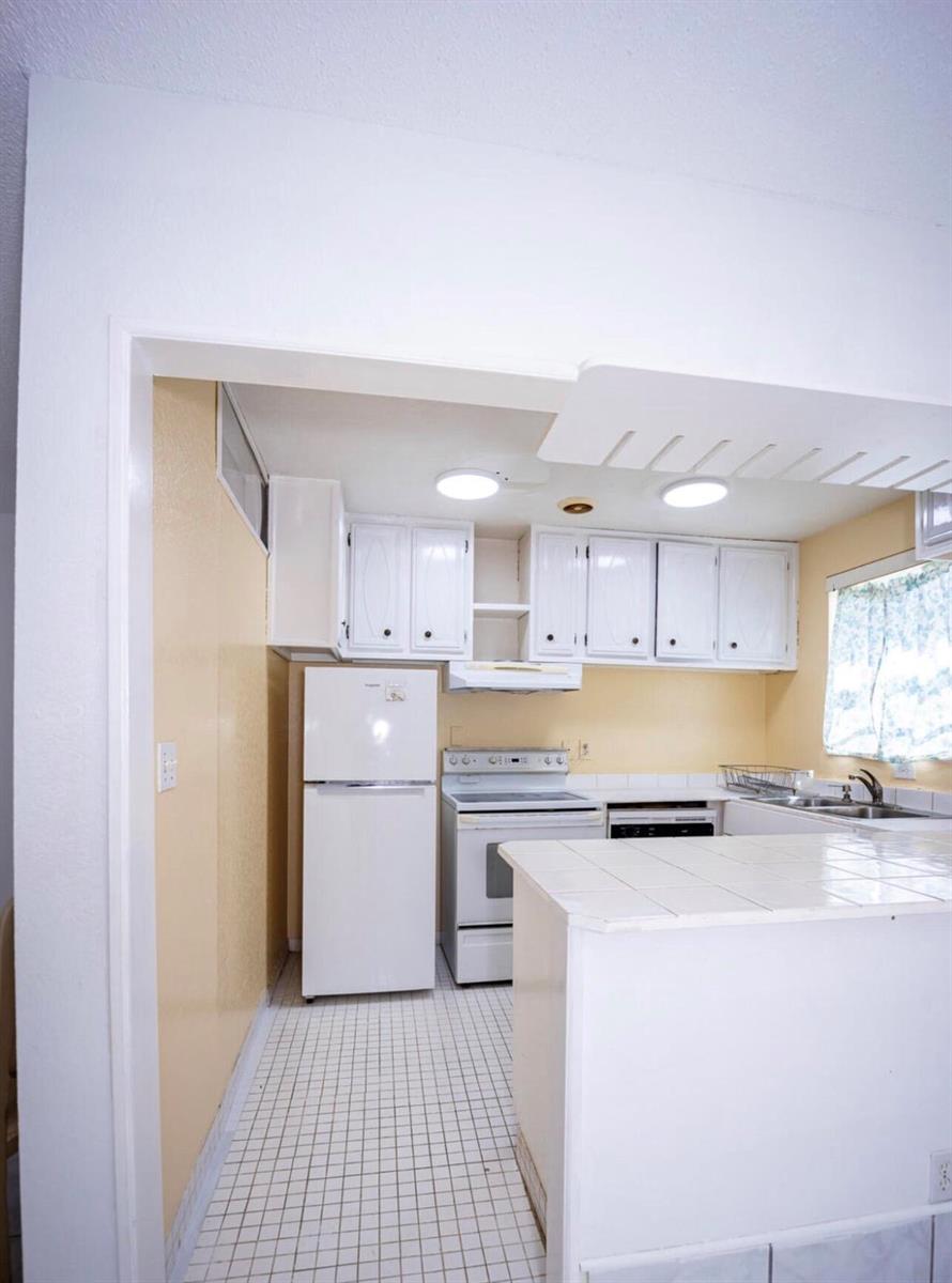 A kitchen features white cabinets, a white refrigerator, a stove, and tiled countertops and flooring — 3240 Ridge Hill Road # C, Boynton Beach FL 33435, BOYNTON BEACH, FL