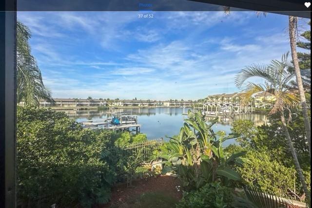 A view of a calm canal with boat docks, lush greenery, and residential buildings beyond — 8720 COVE COURT, TAMPA, FL