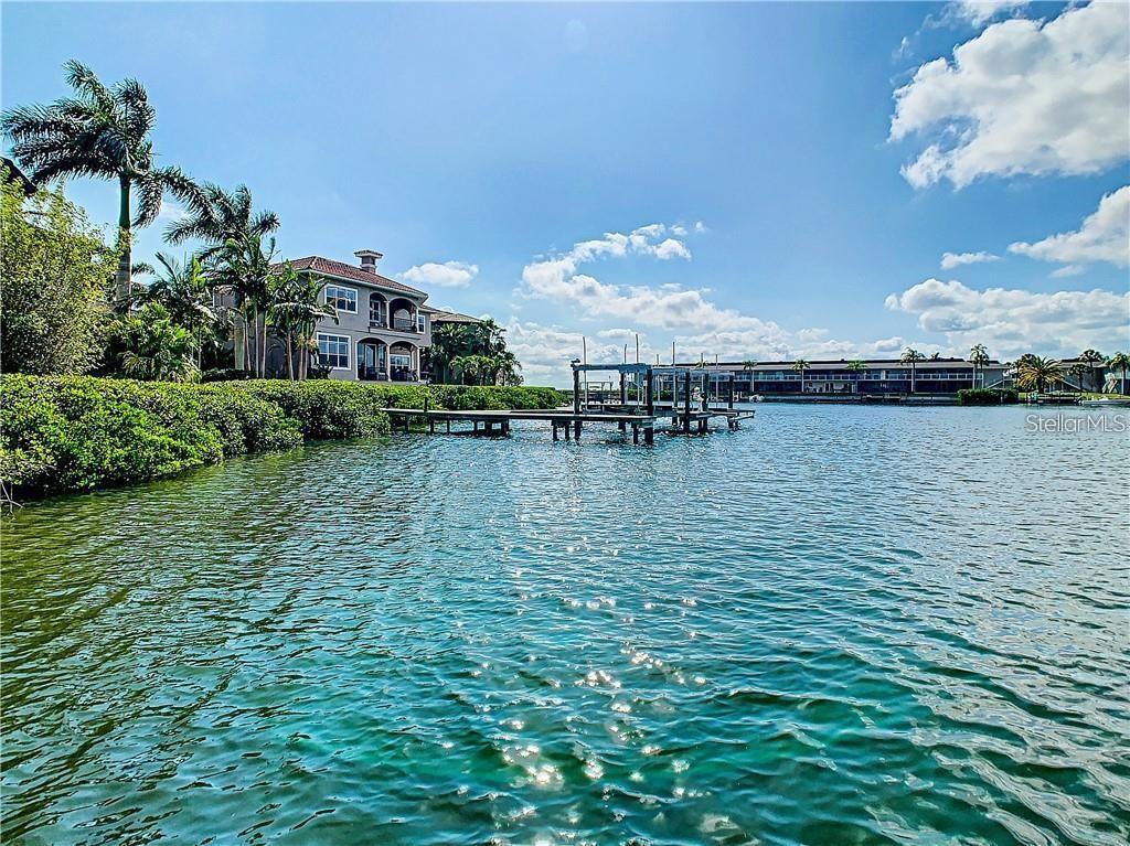A waterfront view of a multi-story house with a private dock and palm trees — 8720 COVE COURT, TAMPA, FL
