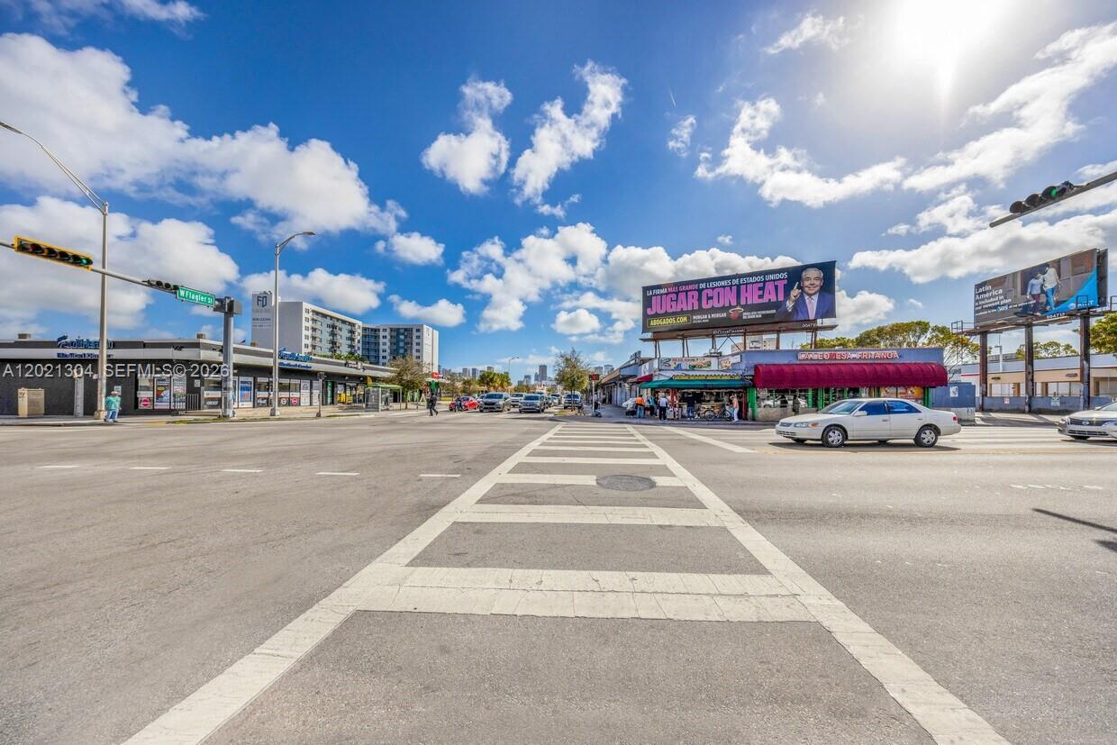 An outdoor street-level view shows a crosswalk at an intersection with commercial buildings and billboards — 1190 W Flagler St, Miami FL 33130, MIAMI, FL