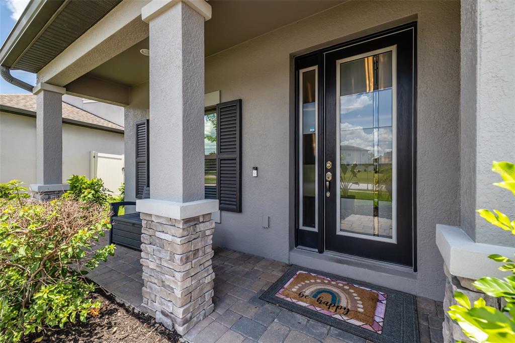 A front porch features a stone-based pillar, a black front door, and a welcome mat — 1686 CHERRY WALK ROAD, LUTZ, FL