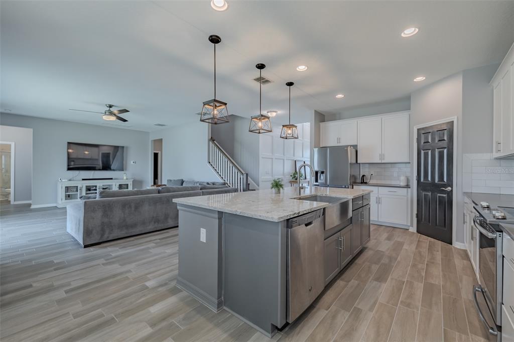 A kitchen with a gray island and stainless steel appliances opens to a living room — 1686 CHERRY WALK ROAD, LUTZ, FL