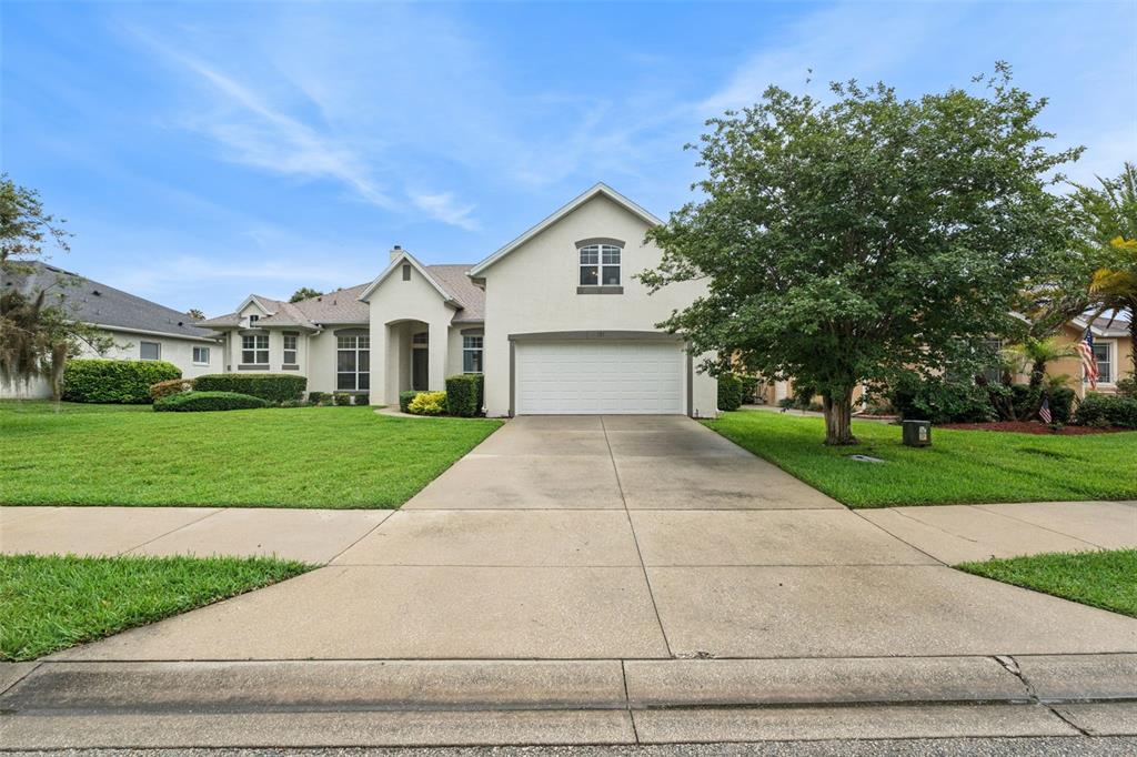 A single-story house with a white garage, beige stucco exterior, and a green front lawn — 135 HICKORY STICK COURT, DEBARY, FL