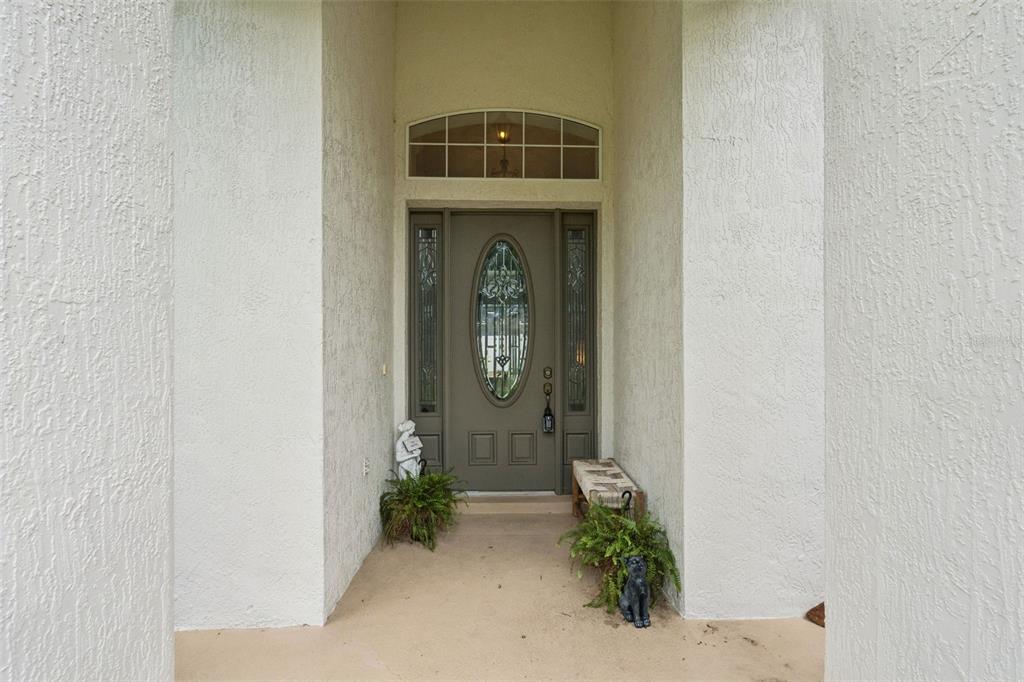 A covered entryway features a gray front door with an oval glass insert and sidelights — 135 HICKORY STICK COURT, DEBARY, FL