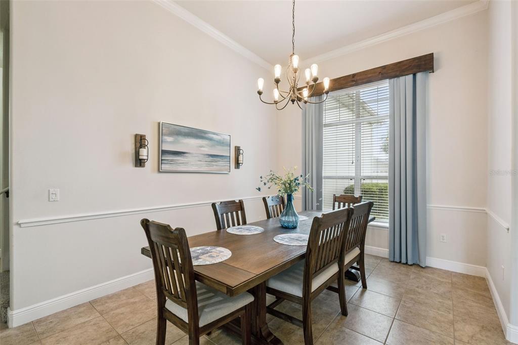 A dining room features a wooden table, six chairs, a chandelier, and a large window — 135 HICKORY STICK COURT, DEBARY, FL