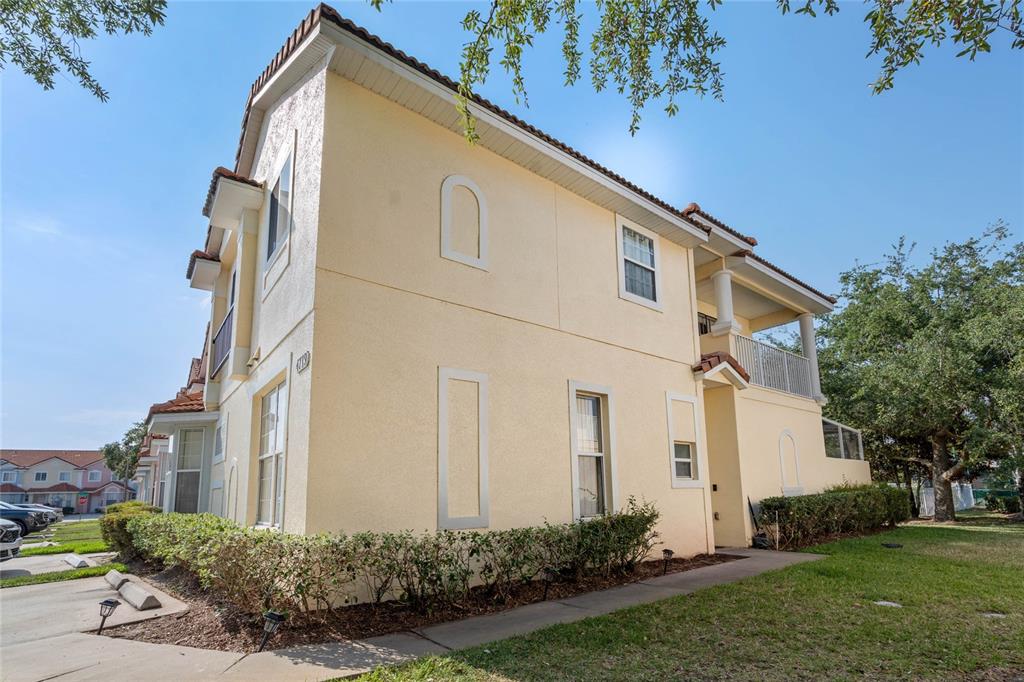 A two-story stucco townhouse with a tiled roof, balcony, and landscaped front yard — 4719 HEMINGWAY HOUSE STREET, KISSIMMEE, FL