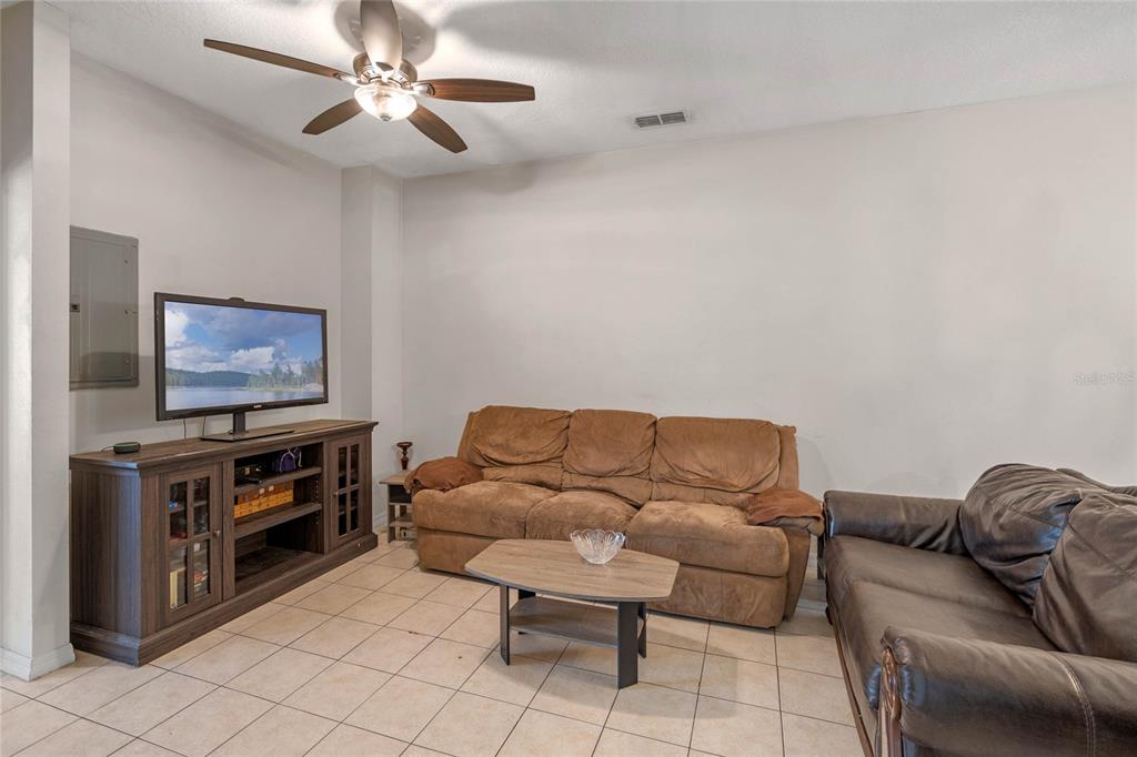A living room features tile flooring, a ceiling fan, a television console, and two sofas — 4719 HEMINGWAY HOUSE STREET, KISSIMMEE, FL