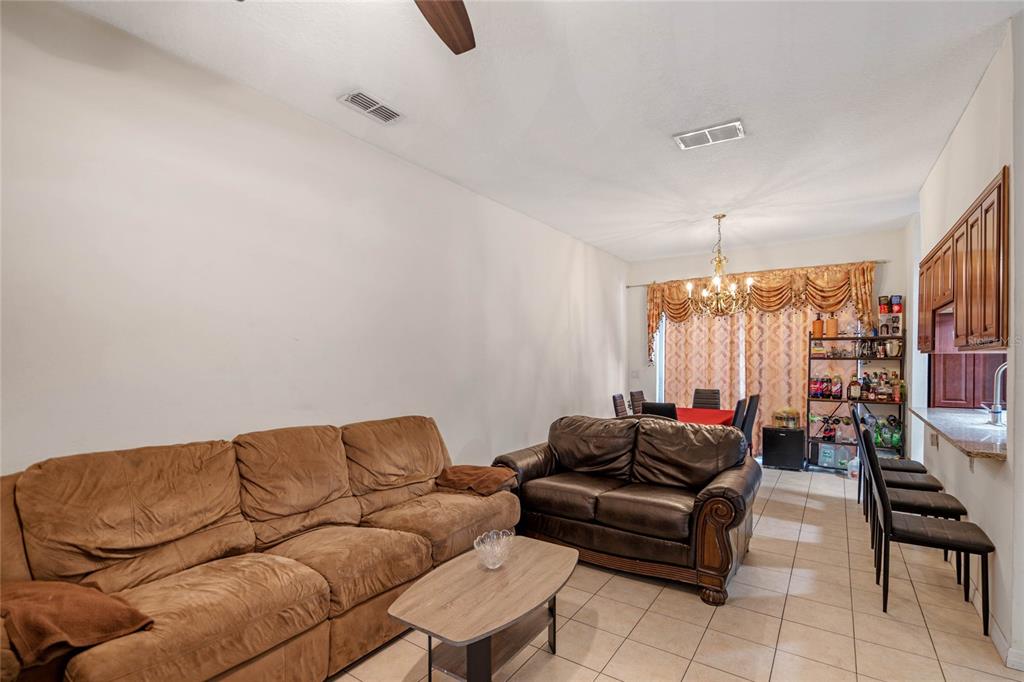 A living and dining area features tile flooring, a brown sofa, and a breakfast bar — 4719 HEMINGWAY HOUSE STREET, KISSIMMEE, FL