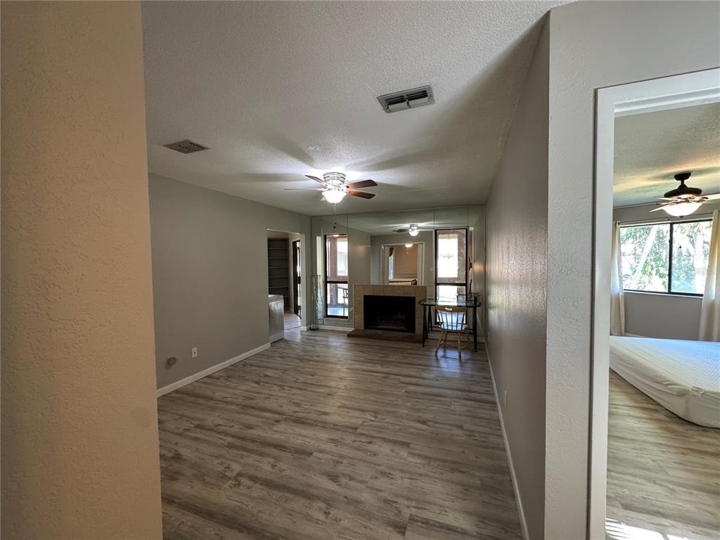 A living room with light wood-look flooring, a fireplace, mirrored walls, and a ceiling fan — 22 MID OAKS CIRCLE UNIT 22, PALM COAST, FL