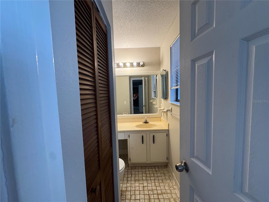 A bathroom features a vanity with a sink, a mirror, and louvered closet doors — 22 MID OAKS CIRCLE UNIT 22, PALM COAST, FL