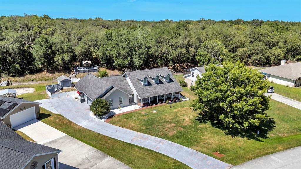 An aerial view shows a gray house with a long driveway and a large tree — 1413 HIDDEN CREEK LANE, WINTER HAVEN, FL