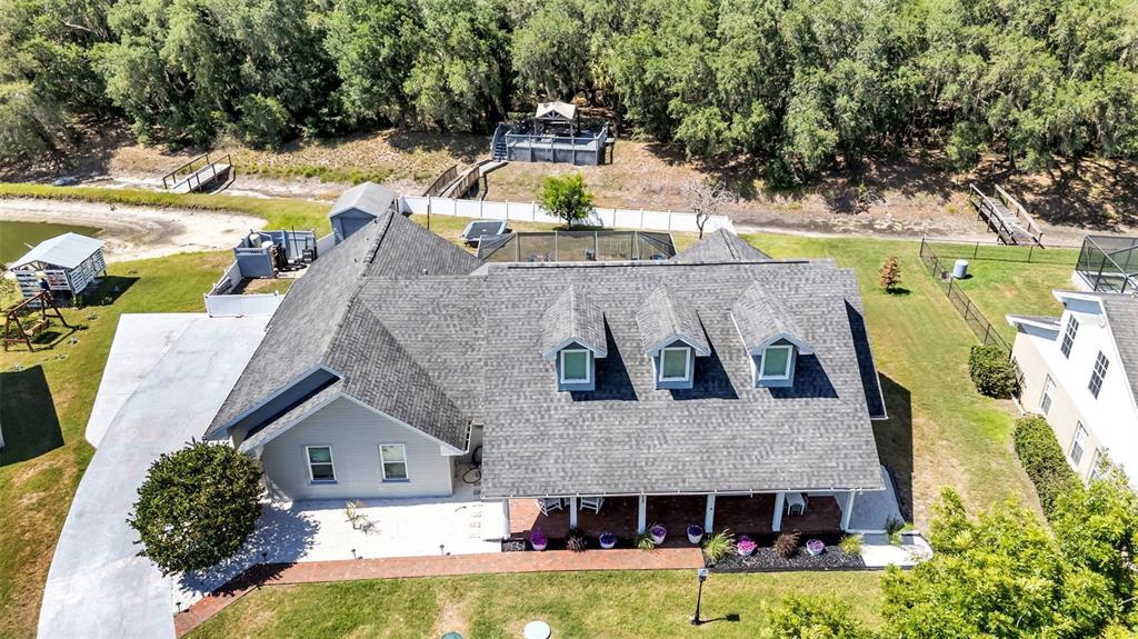 An aerial view shows a house with a gray shingled roof, dormers, and a porch — 1413 HIDDEN CREEK LANE, WINTER HAVEN, FL