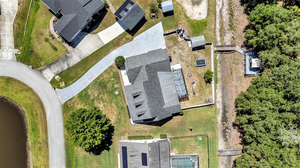 An aerial view shows a residential house with a pool enclosure and surrounding yard — 1413 HIDDEN CREEK LANE, WINTER HAVEN, FL