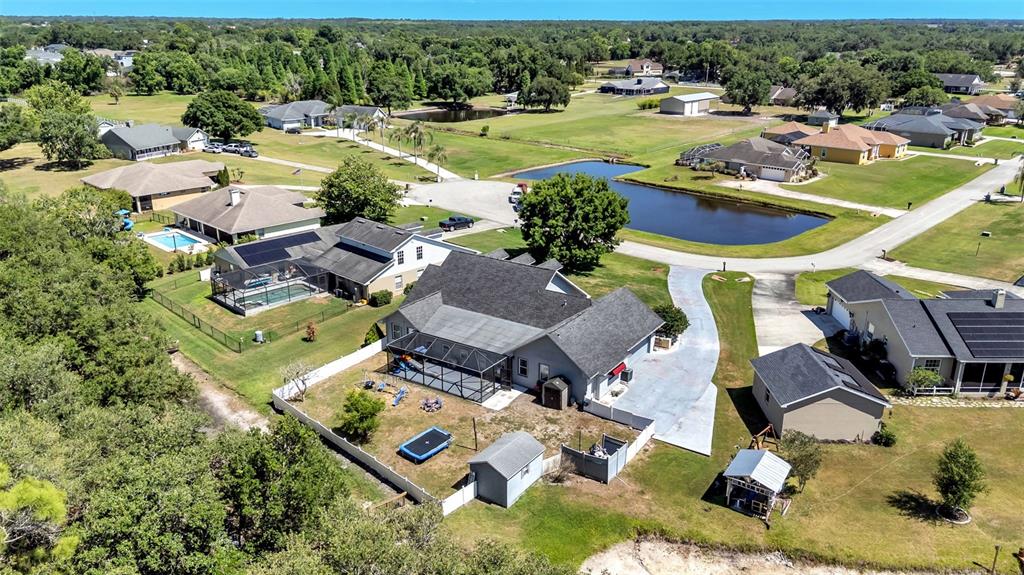 An aerial view shows several suburban houses with pools, fenced yards, and a small pond — 1413 HIDDEN CREEK LANE, WINTER HAVEN, FL
